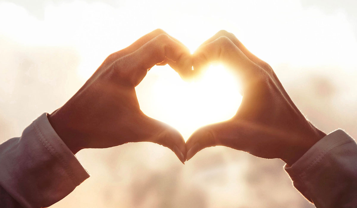 Hands held up to the sun in the shape of a heart