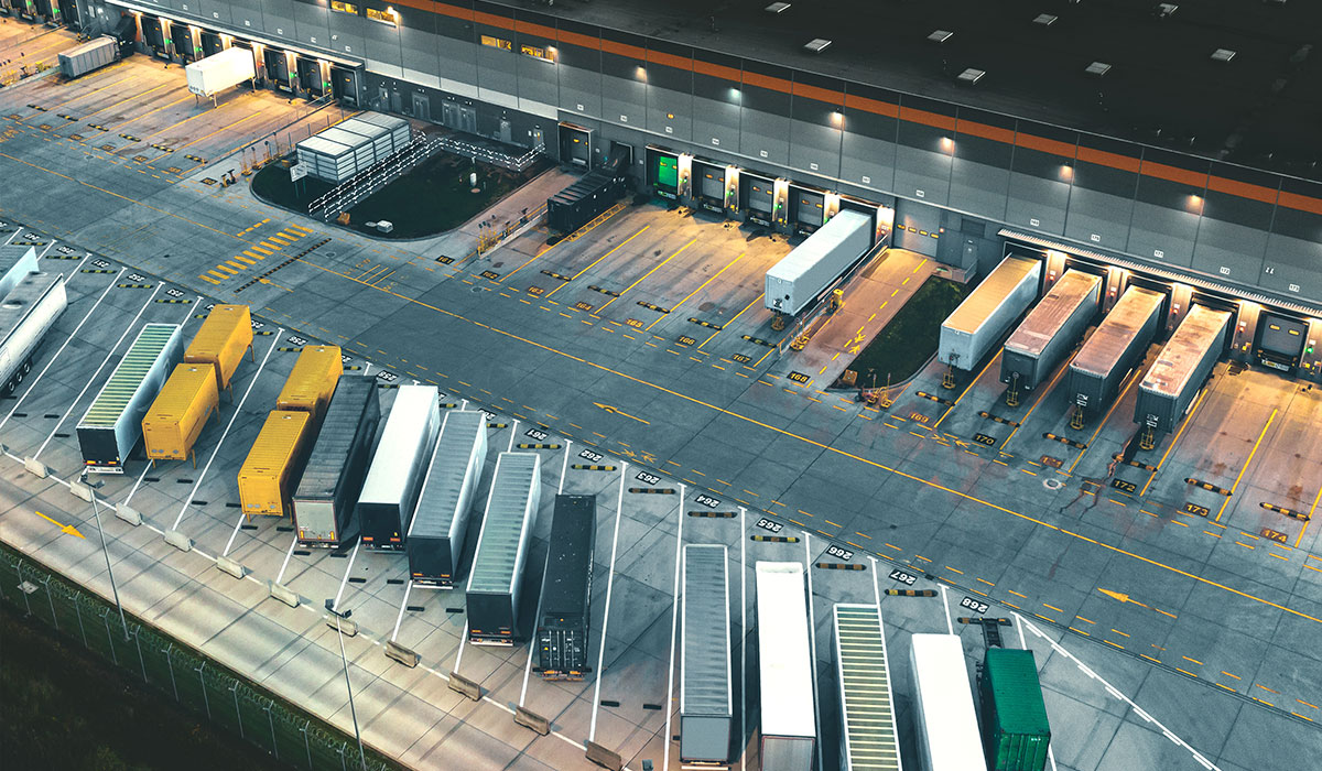 Aerial view of large warehouse with multiple trailers parked at loading bays.