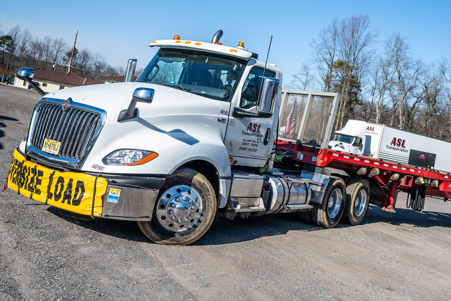 Rental-03 Empty ASL flatbed truck with "oversized load" banner on its front bumper.
